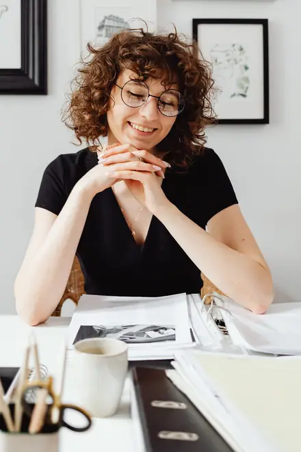 A Sunshine Coast business owner smiling at her desk, paperwork in front of her
