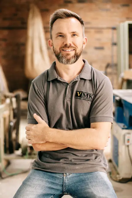 A Sunshine Coast woodworker smiling in his workshop, arms folded